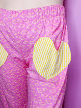 Load image into Gallery viewer, Pink pants with yellow pop tart pattern with yellow gingham heart shaped pockets on a mannequin against a pink background