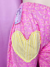Load image into Gallery viewer, Pink pants with yellow pattern on a pink background