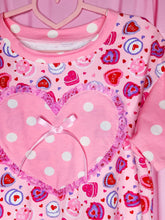 Load image into Gallery viewer, Pink t-shirt with heart cake designs and polka dots on a pink background