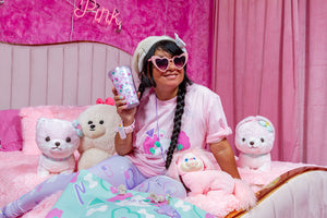 latina woman modeling pastel dog print clothing and t-shirt on a bed in pink room