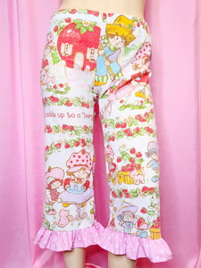 Patterned pants with ruffle hem against a pink background