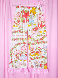 Capri pants with cartoon characters and strawberry pattern on a pink background