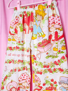 Elastic waisted pants with strawberry shortcake design on a pink background