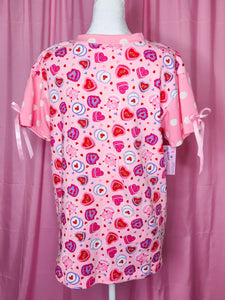 Pink boxy top with heart cake pattern on a mannequin against a pink background
