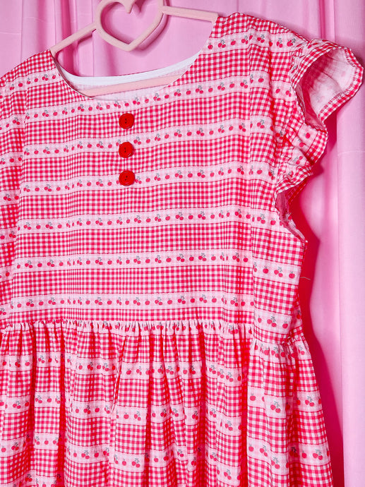 Red and white checkered dress with buttons on a pink background