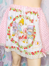 Load image into Gallery viewer, Pink and white Strawberry Shortcake themed shorts featuring a colorful cartoon character print, strawberry and rose floral borders, lace trim, and pink polka dot side panels.