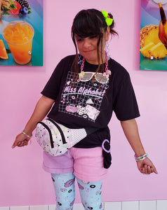 woman modeling t-shirt with miss alphabet logo, pillows, and pink 90s barbie boombox print