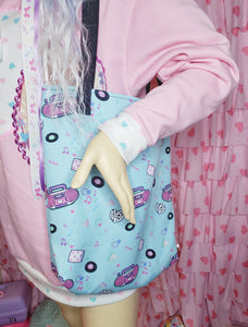 blue tote bag with pink boomboxes, modeled on a mannequin wearing a pink sweater
