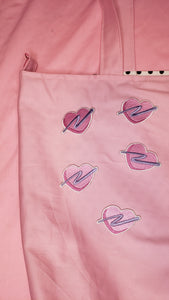 embroidered pink heart patches with purple swoosh on a pink tote bag