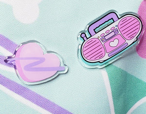 Acrylic pins with pink boombox image and pink swoosh heart on a mint green tote bag with dogs and bones and 90's motifs