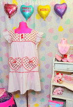 Load image into Gallery viewer, white nightie dress with red hearts and teddy bears on a mannequin against a pastel heart backdrop with pastel heart balloons above, next to a white wicker shelf full of accessories and valentine plushies