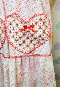 closeup of heart shaped pockets with red plaid print and teddy bears on a white nightie dress with tiny red hearts