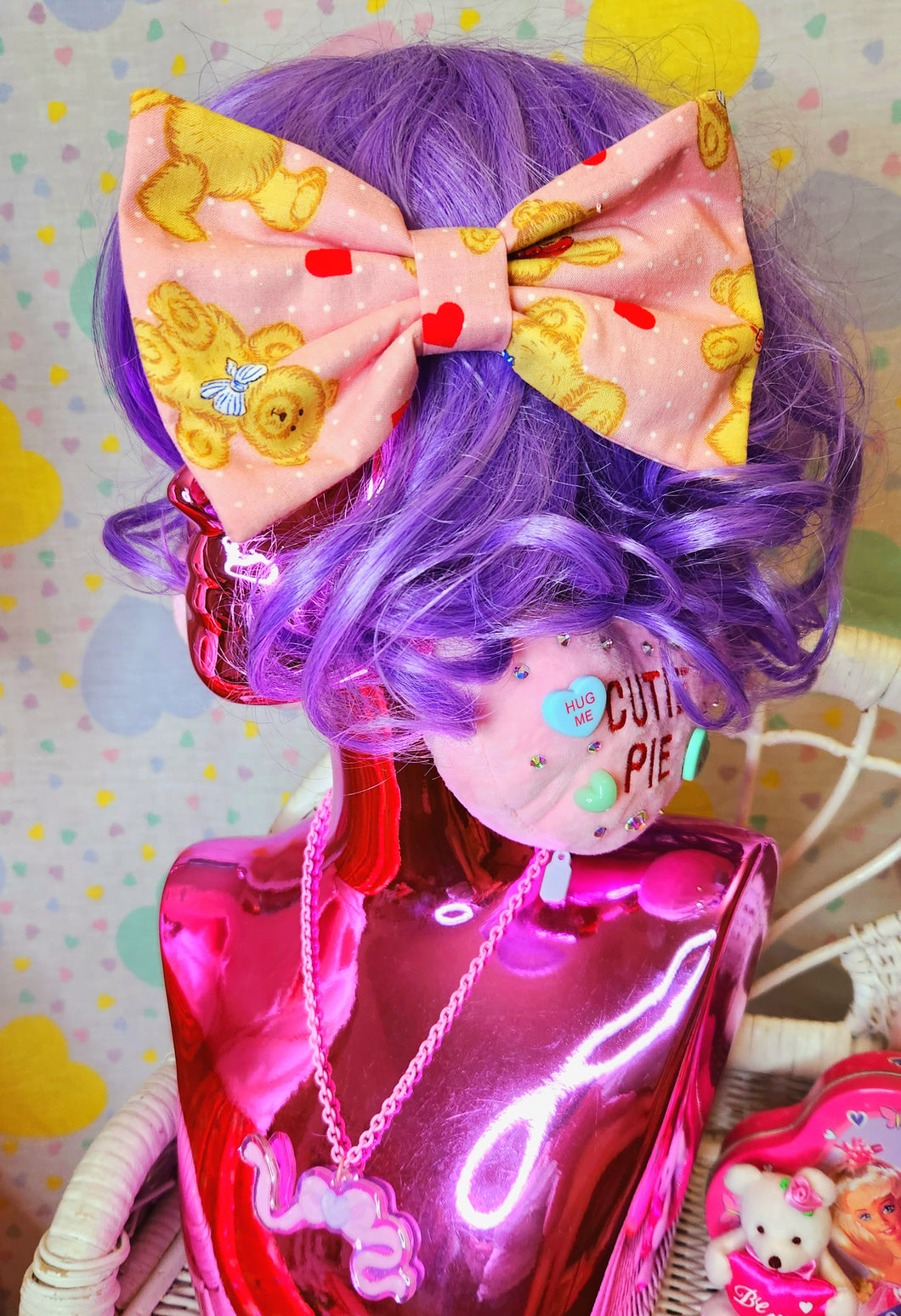 Pink Valentine's Day hair bow with hearts and teddy bears, on a lavender haired shiny pink mannequin bust