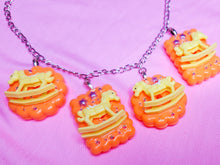 Load image into Gallery viewer, silver chain necklace with orange cracker biscuit charms with yellow rocking horses and rhinestones