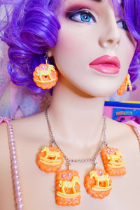 lavender haired mannequin modeling orange cracker biscuit necklace and matching earrings