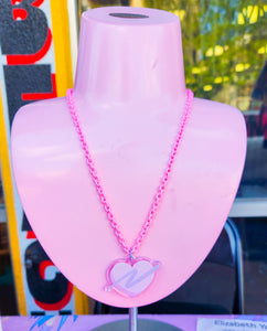 pink enamel chain necklace with pink and lavender glitter swoosh heart acrylic pendant on pink jewelry stand