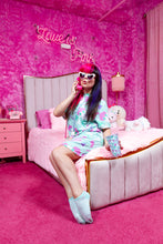Load image into Gallery viewer, caucasian woman with brightly colored hair posing with a phone on a bed in pink room wearing a mint green dress with dog print