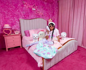 latina woman modeling pastel dog and bone print outfit and tote bag on bed in pink room