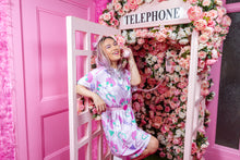 Load image into Gallery viewer, Asian woman wearing a pink dress with dog print, posing in a rose covered pink phone booth