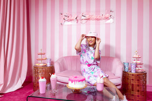 Asian woman modeling a dog print dress and pink bucket hat against a pink and white background
