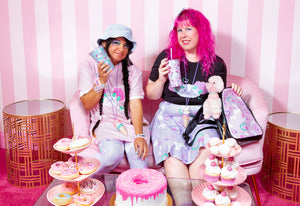 two women sharing drinks wearing pastel clothing