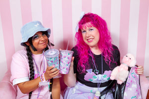 pastel friends in dog and bone print clothing posing with matching tumblers in front of pink striped background
