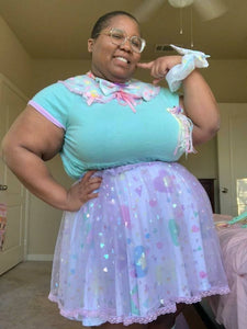 african american nonbinary wearing a mint green top with layered heart skirts
